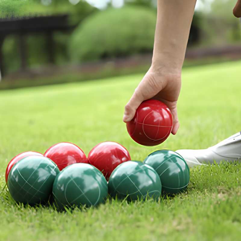 Bocce Resin 6 red and green resin bocce balls on grass with a hand